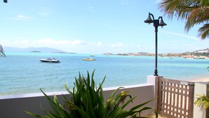 A coastal view with a balcony overlooking turquoise waters, boats, and distant land. - The Boardroom Beach Bungalows (Koh Samui)