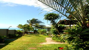 A tropical garden with a pathway leading to a building, surrounded by lush greenery and palm trees. - The Boardroom Beach Bungalows (Koh Samui)