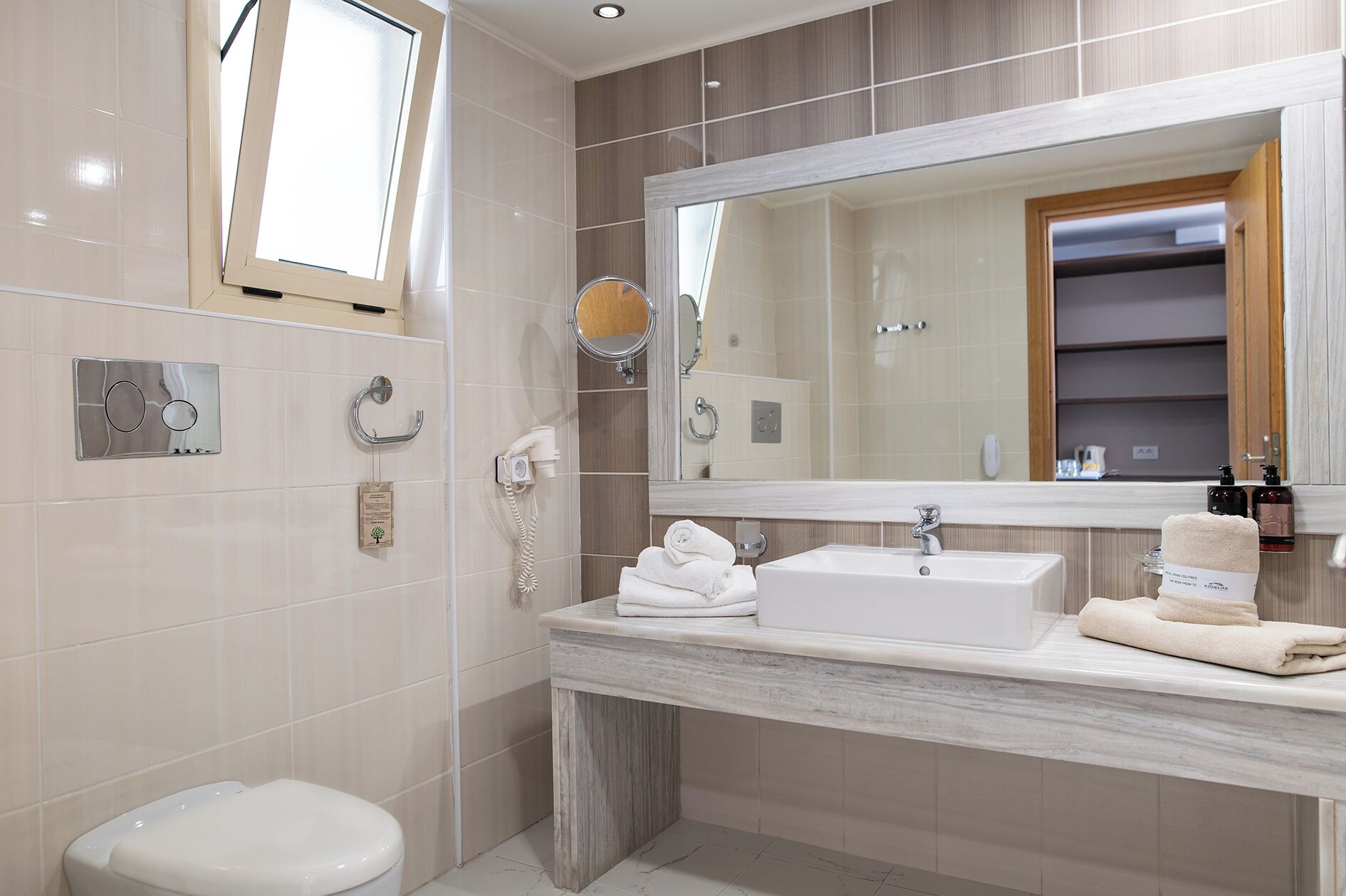 A modern bathroom with a toilet, a sink with a mirror above it, and a towel rack.