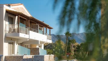 A two-story building with a balcony, stone walls, and a view of mountains.