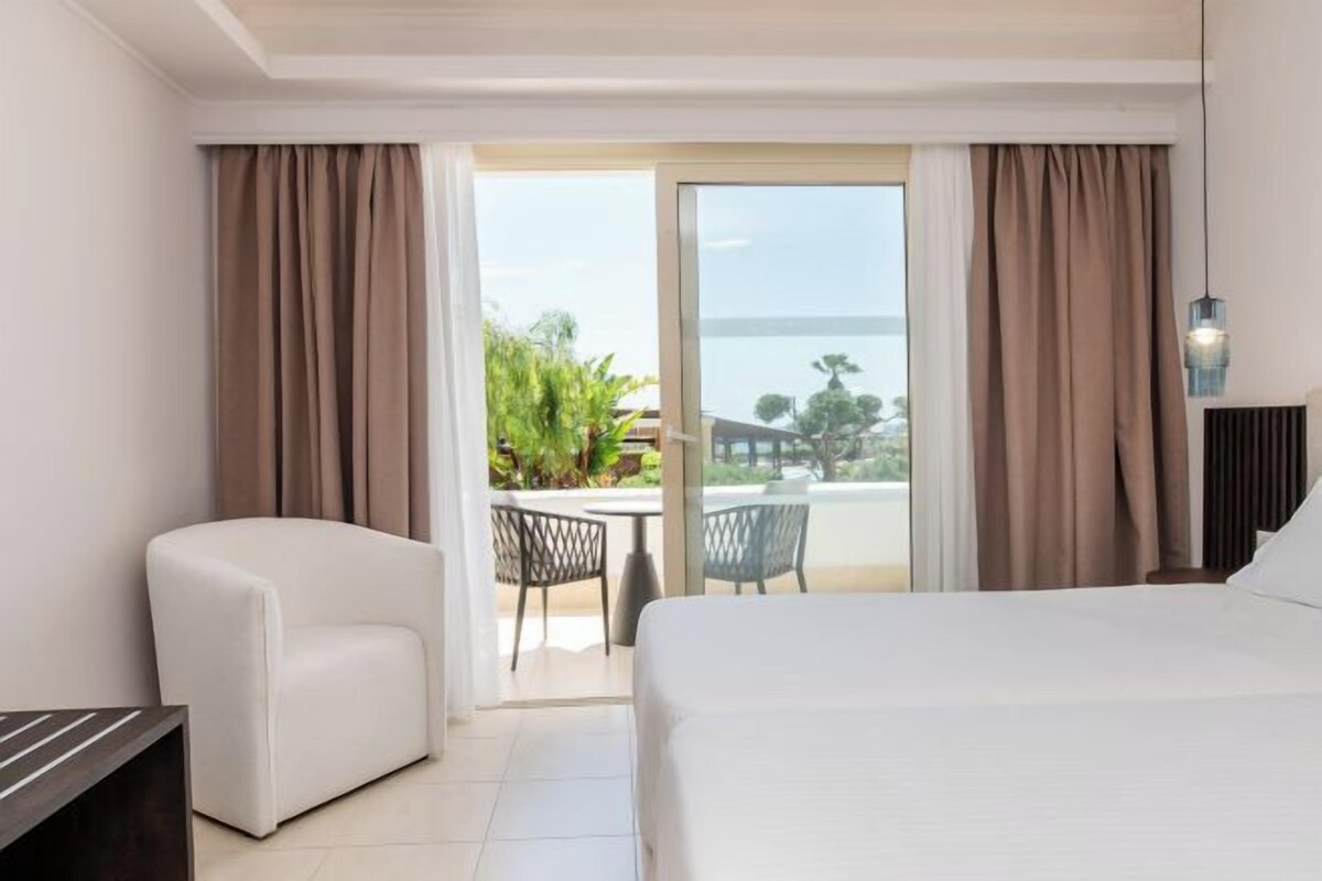 Une chambre d’hôtel avec un lit, une chaise, un bureau et une vue sur l’extérieur grâce à une porte coulissante.