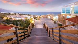 A wooden staircase leading to a building with a view of the sea. - Grand Blue Beach Hotel (Kos)