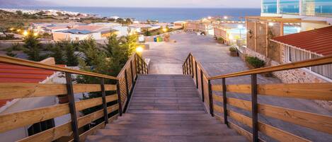 A wooden staircase leading to a building with a view of the sea.