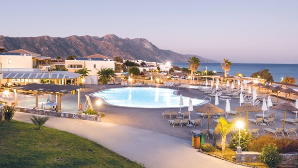 A resort with a large pool, sun loungers, umbrellas, and a view of the mountains. - Grand Blue Beach Hotel (Kos)