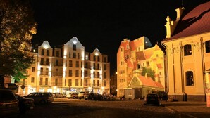 A cobblestone street lined with historic buildings at night. - Hotel Śródka (Poznan)