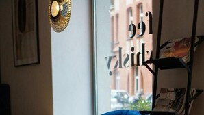 A cozy interior with a blue armchair, a yellow chair, and a small round table with a cup. - Hotel Śródka (Poznan)
