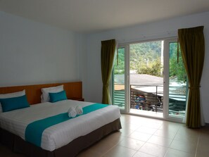 A hotel room with a bed, curtains, and a view of a balcony and greenery outside. - Wandee Bed and Breakfast - Hostel (Takua Pa)