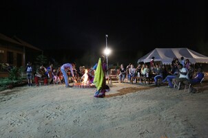 A group of people gathered around a fire in an outdoor setting at night.