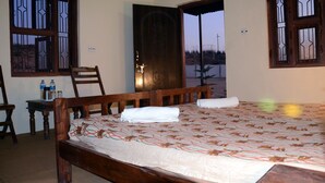 A bedroom with a wooden bed, a desk with a chair, and a window with decorative bars. - Pushkar Adventure Desert Camp (Peesangan)