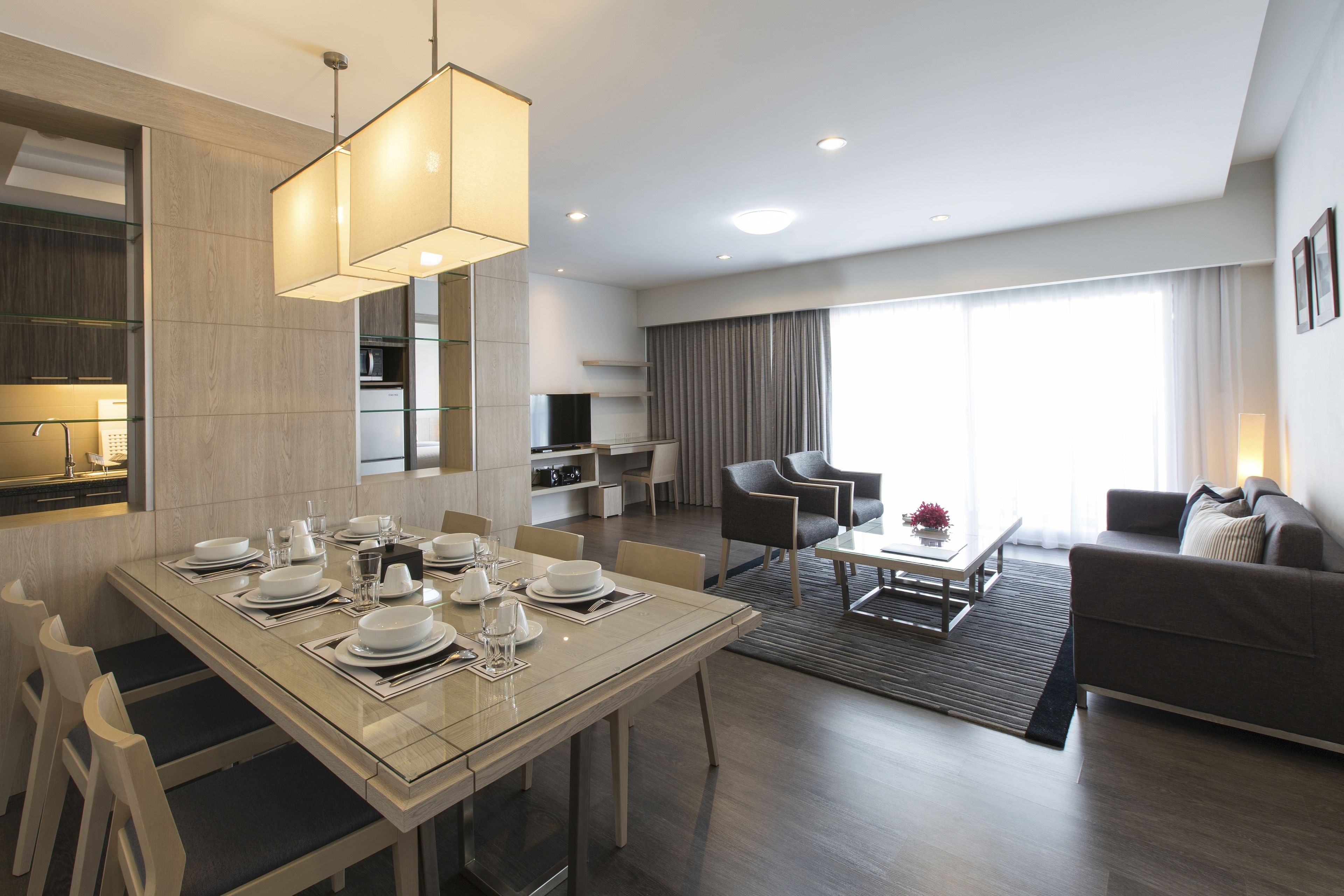 A modern hotel room with a dining area, a living room, and a kitchen.