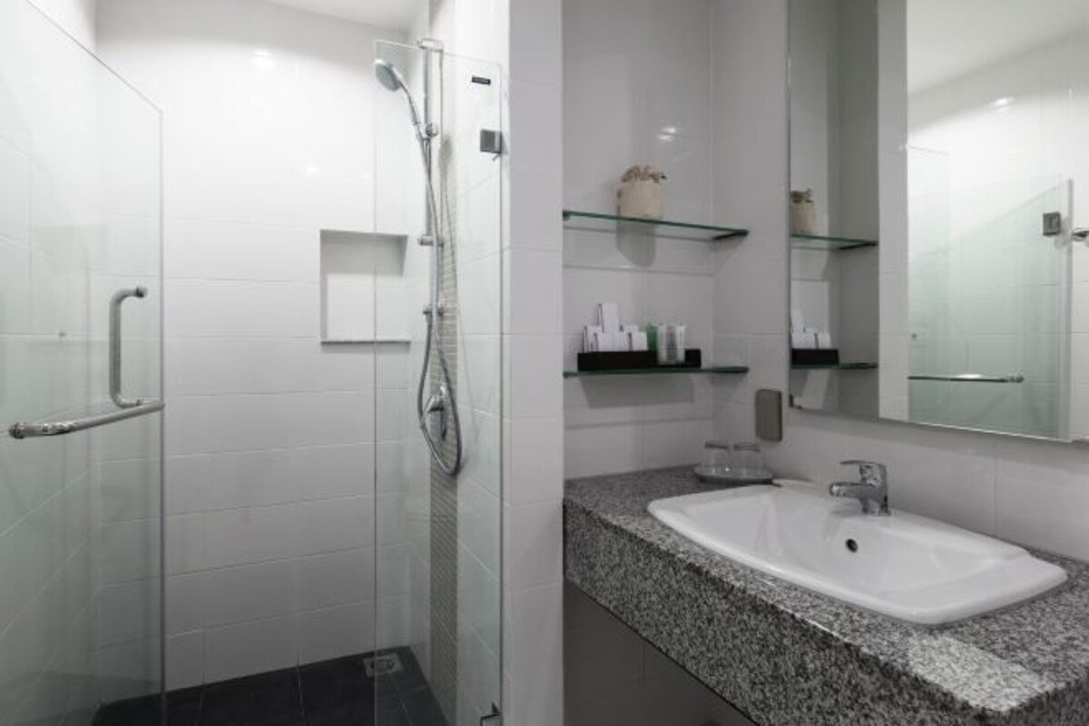 A modern bathroom with a glass shower enclosure, a granite countertop sink, and glass shelves above the sink.