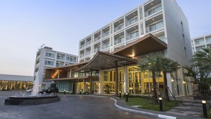 Een modern hotel met een centrale binnenplaats, een fontein en een overdekte ingang.