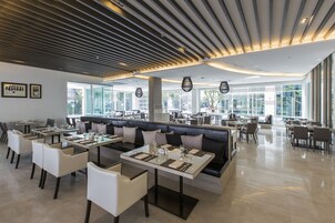 Un restaurante moderno con una mezcla de cabinas y mesas, un techo alto con listones de madera y grandes ventanales que ofrecen vistas al exterior.