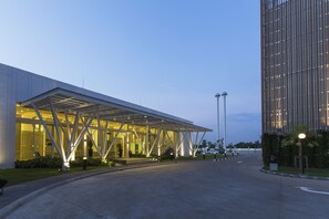 A modern building with a covered entrance and a tall structure nearby.