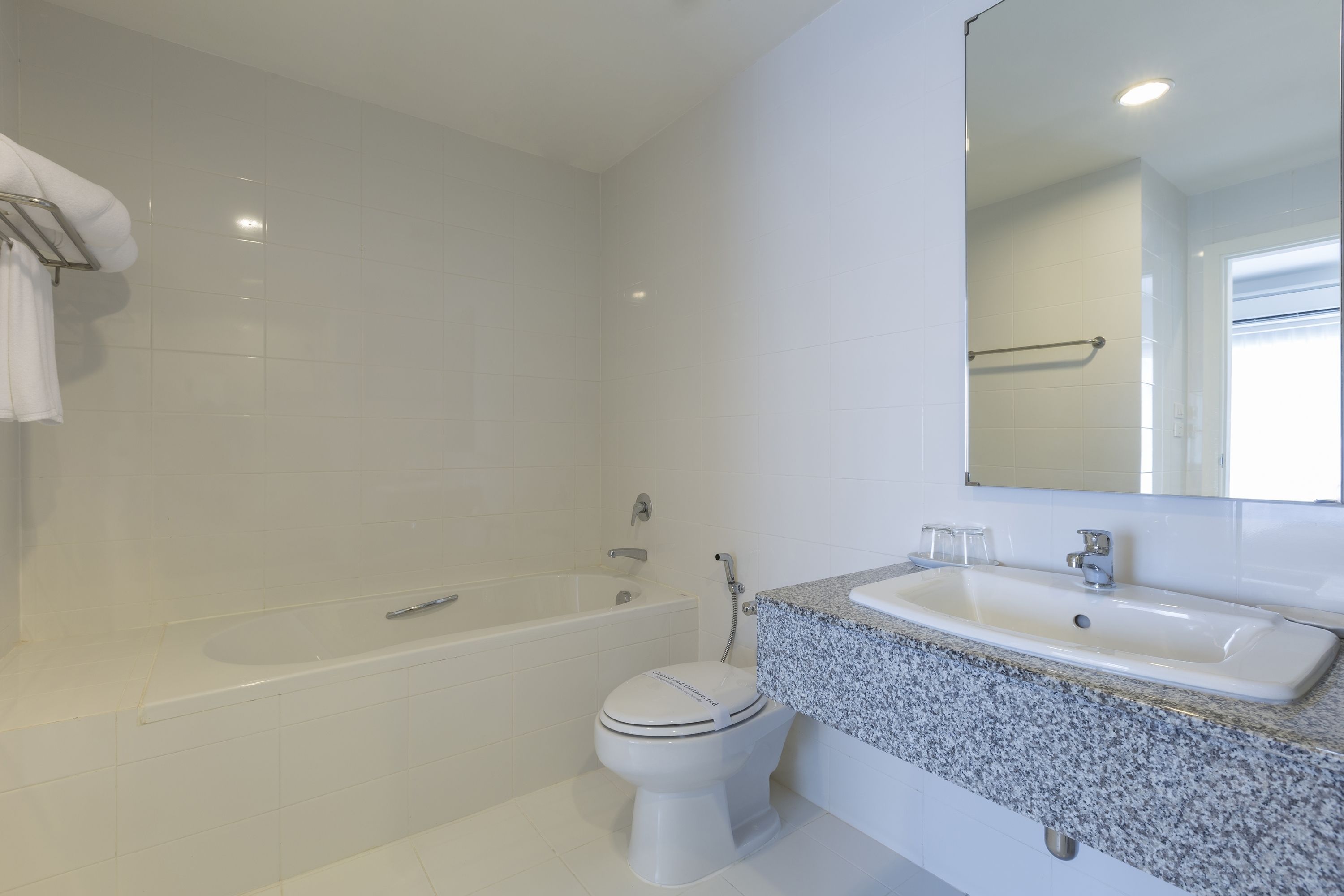 Un baño con una bañera blanca, un inodoro blanco y una encimera de granito con un lavabo.