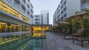 Een moderne hotelbinnenplaats met een zwembad, ligbedden en parasols.