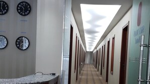 Un pasillo de hotel con relojes a la izquierda, un mostrador de recepción y una alfombra estampada.