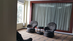 Una habitación con dos sillones de mimbre, una mesita y un ventanal con cortinas.