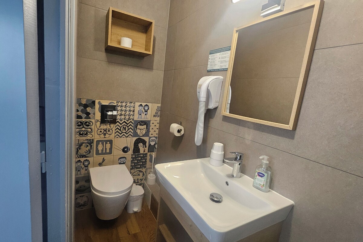 A bathroom with a toilet, sink, and a mirror.