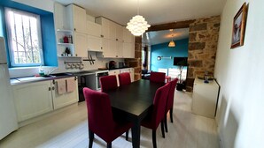 Una cocina moderna con armarios blancos, encimera negra y sillas rojas alrededor de una mesa de comedor central.