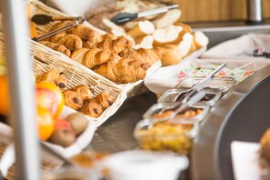 A buffet with various food items including croissants, bread, and fruits. - Hôtel les Pieux (Les Pieux)