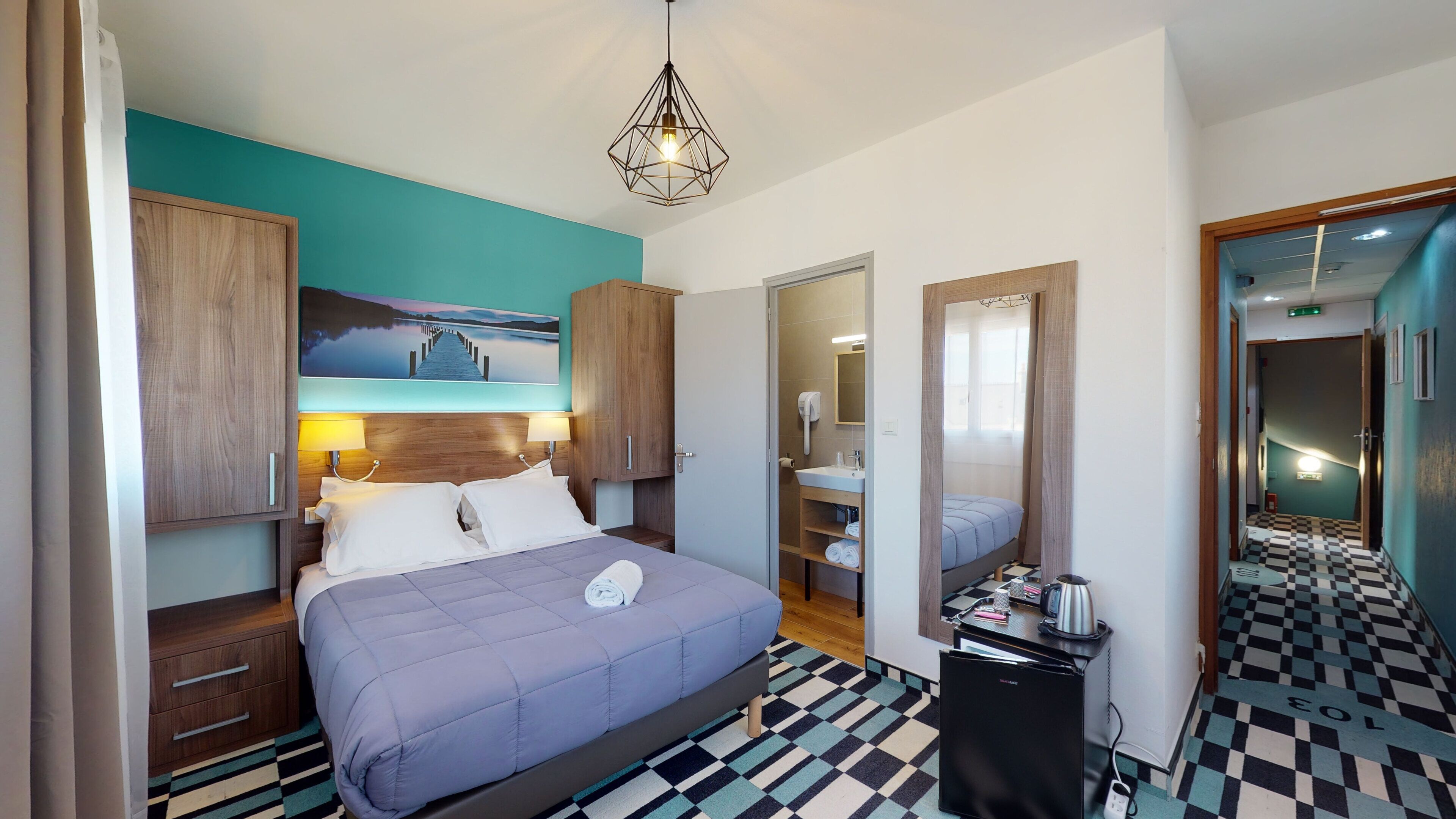 A hotel room with a bed, a desk, a chair, a wardrobe, a bathroom, and a checkered floor.
