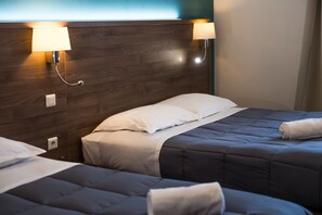 A hotel room with a wooden headboard, two beds with grey bedding, and wall-mounted lamps. - Hôtel les Pieux (Les Pieux)