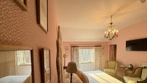 A hotel room with two beds, a chandelier, a television, and a window with curtains. - The Salwey Arms (Ludlow)