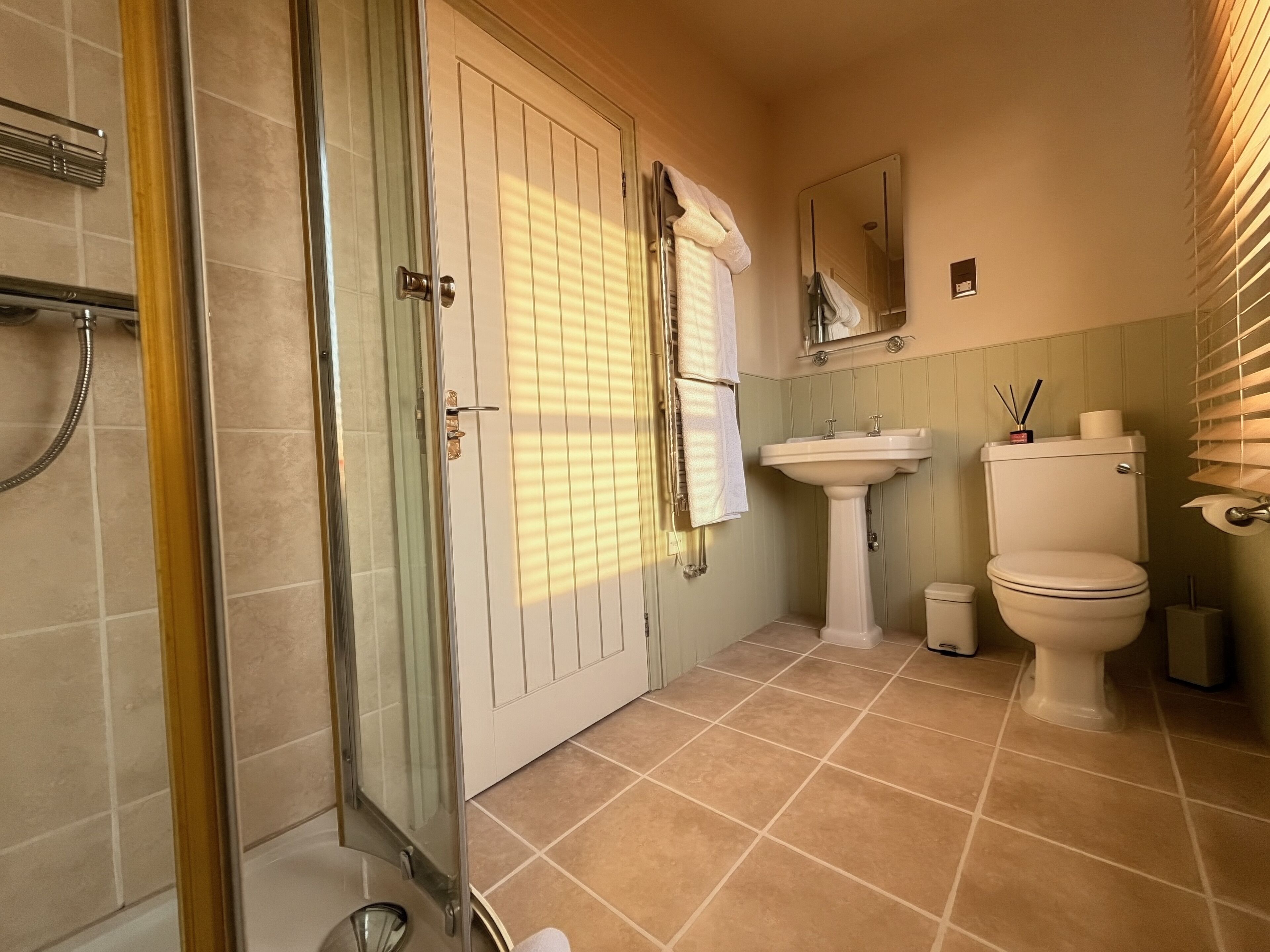 Un baño con cabina de ducha de vidrio, un lavabo, un inodoro y un espejo.
