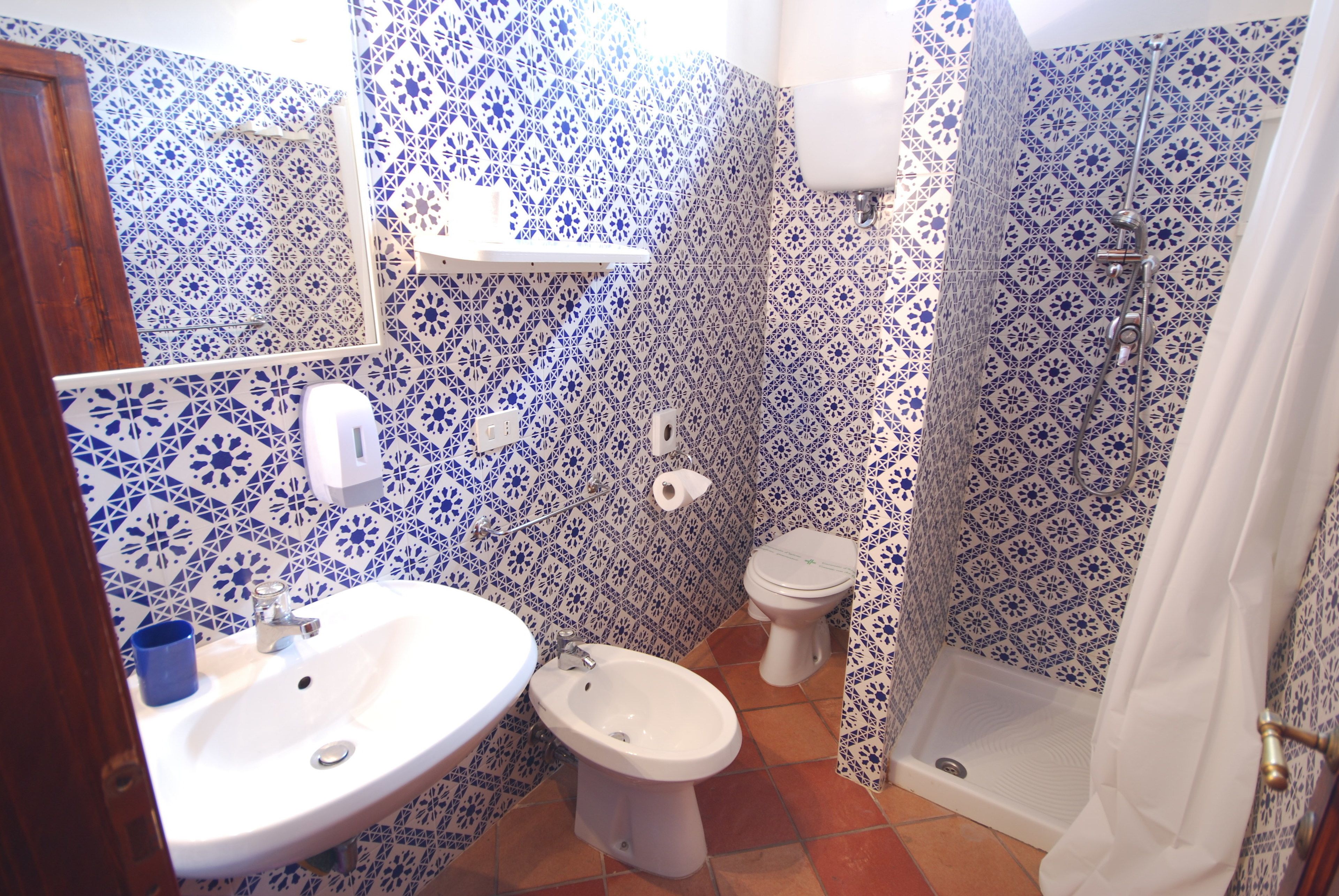 A bathroom with a sink, bidet, toilet, and shower.