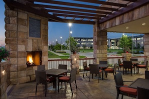 An outdoor patio with stone walls, a fire feature, and outdoor seating. - Hyatt Place DFW (Dallas)