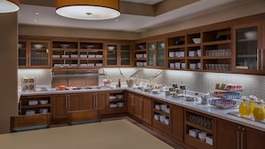 A modern kitchen with wooden cabinets, a white countertop, and various kitchen appliances. - Hyatt Place DFW (Dallas)