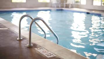 Una piscina interior con barandillas de metal y un borde de azulejos.