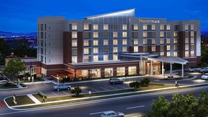 A modern Hyatt Place hotel with a prominent glass facade, multiple floors, and a covered entrance area. - Hyatt Place DFW (Dallas)