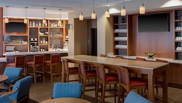 Eine Bar mit Holzküchenmöbeln, einer Theke mit verschiedenen Flaschen und einem Fernsehbildschirm.