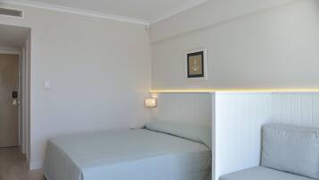 Un dormitorio con una cama, una mesita de noche, una lámpara de pared y un cuadro enmarcado.
