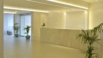A modern reception area with a marble reception desk, potted plants, and a clean, minimalist design.