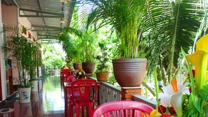 A corridor with red chairs, potted plants, and a tiled floor. - Minh Anh Garden Hotel (Mui Ne)