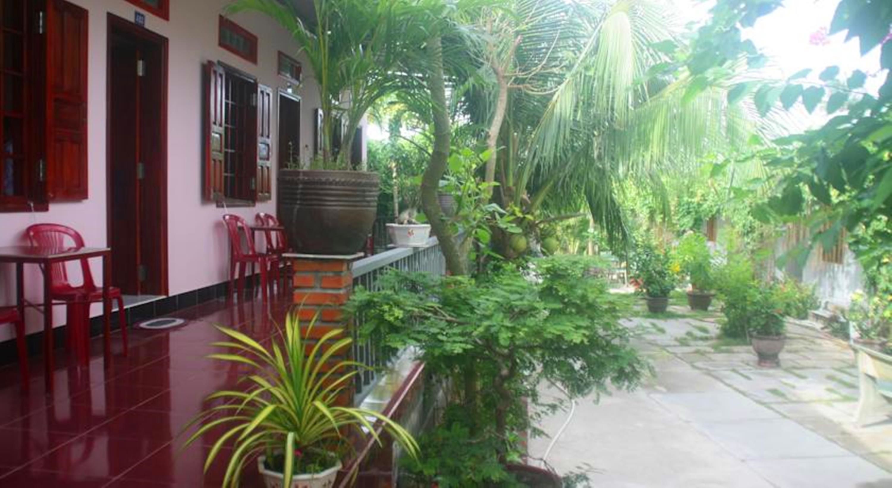 A covered outdoor area with a tiled floor, red chairs, and potted plants.