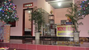 A reception area with a Christmas tree, potted plants, and a sign for 'MINH ANH GARDEN HI-TECH'. - Minh Anh Garden Hotel (Mui Ne)