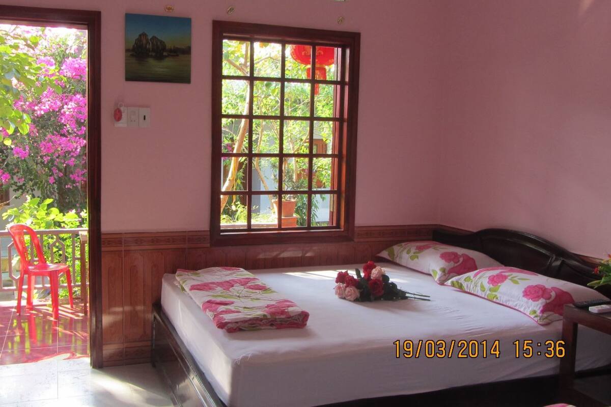 Un dormitorio con cama, ventana, una silla y balcón.