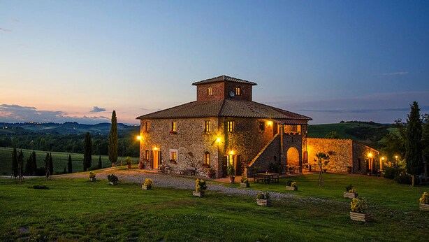 A stone building with a tiled roof, multiple windows, and a staircase leading to an upper level. - Agriturismo Ragoncino (Lajatico)