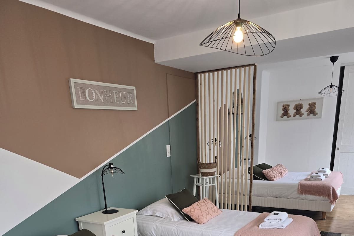 Ein Hotelzimmer mit zwei Betten, einem kleinen Tisch, einem Stuhl, einer Pendelleuchte und einem an der Wand befestigten Schild.