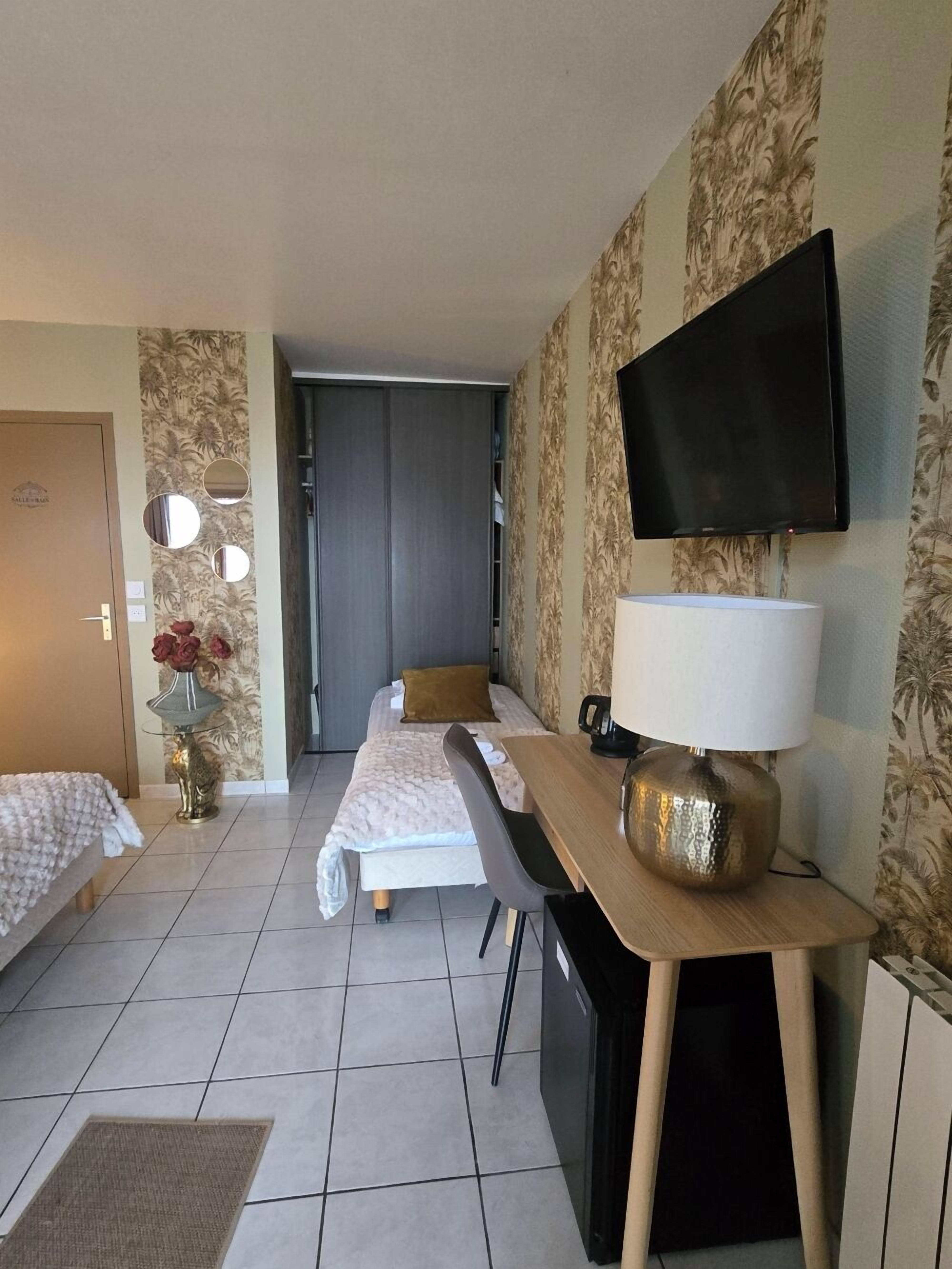 Habitación de hotel con dos camas, un escritorio, una silla, un televisor y un espejo.