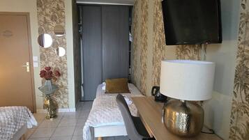 A hotel room with two beds, a desk, a chair, a TV, and a mirror.