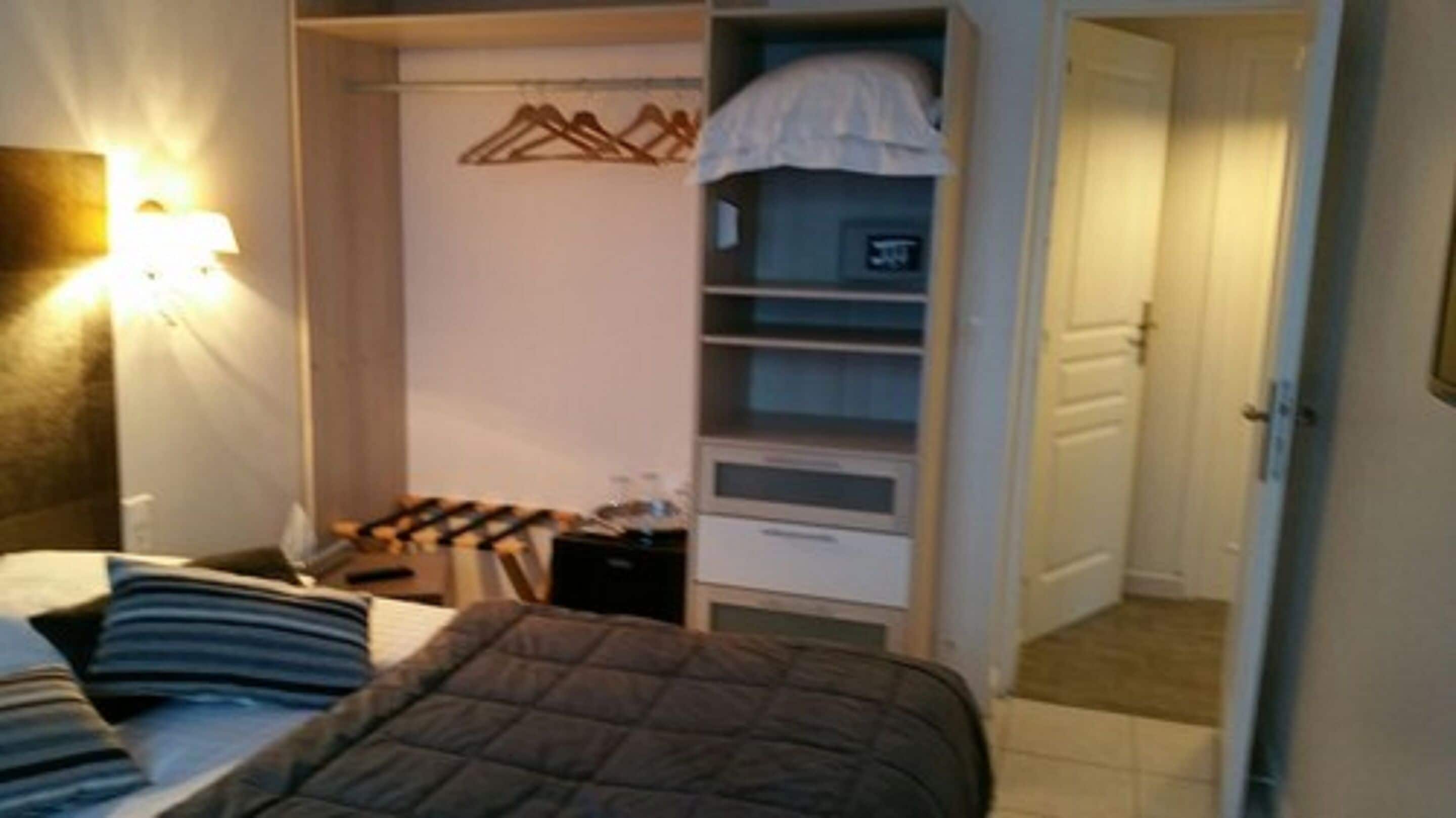 Un dormitorio con cama, armario y mesita de noche.
