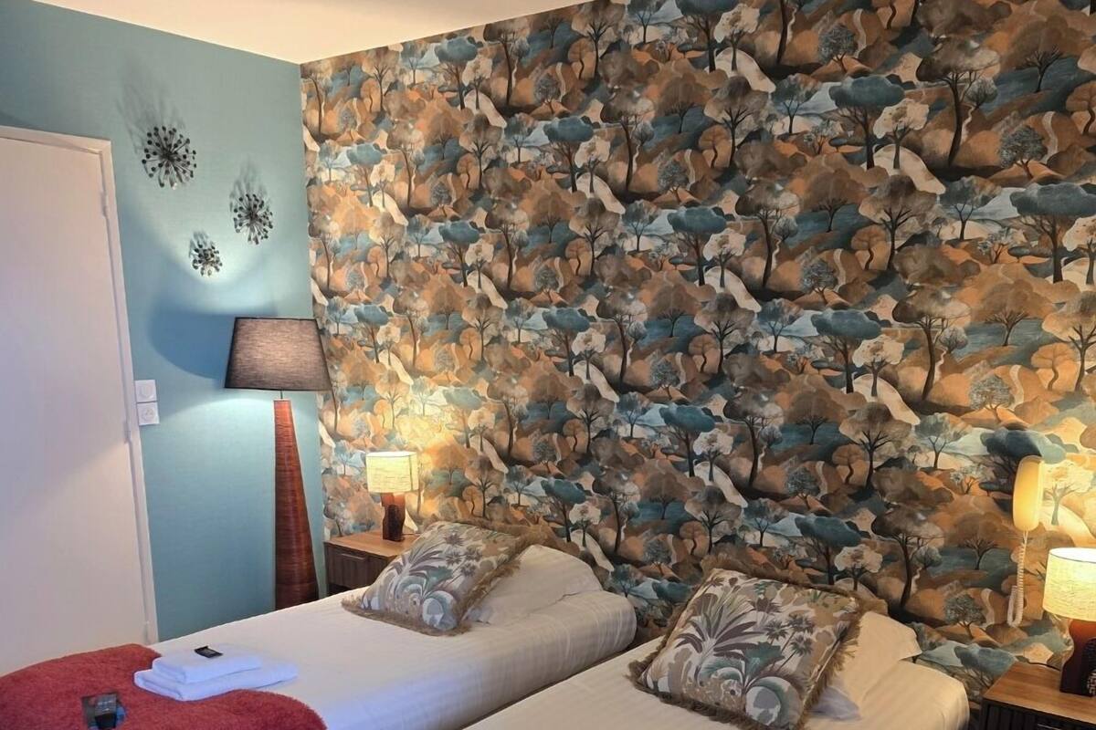 Ein Doppelzimmer mit zwei Betten, jedes mit einer roten Decke und Kissen, einer großen Wandmalerei und Nachttischlampen.