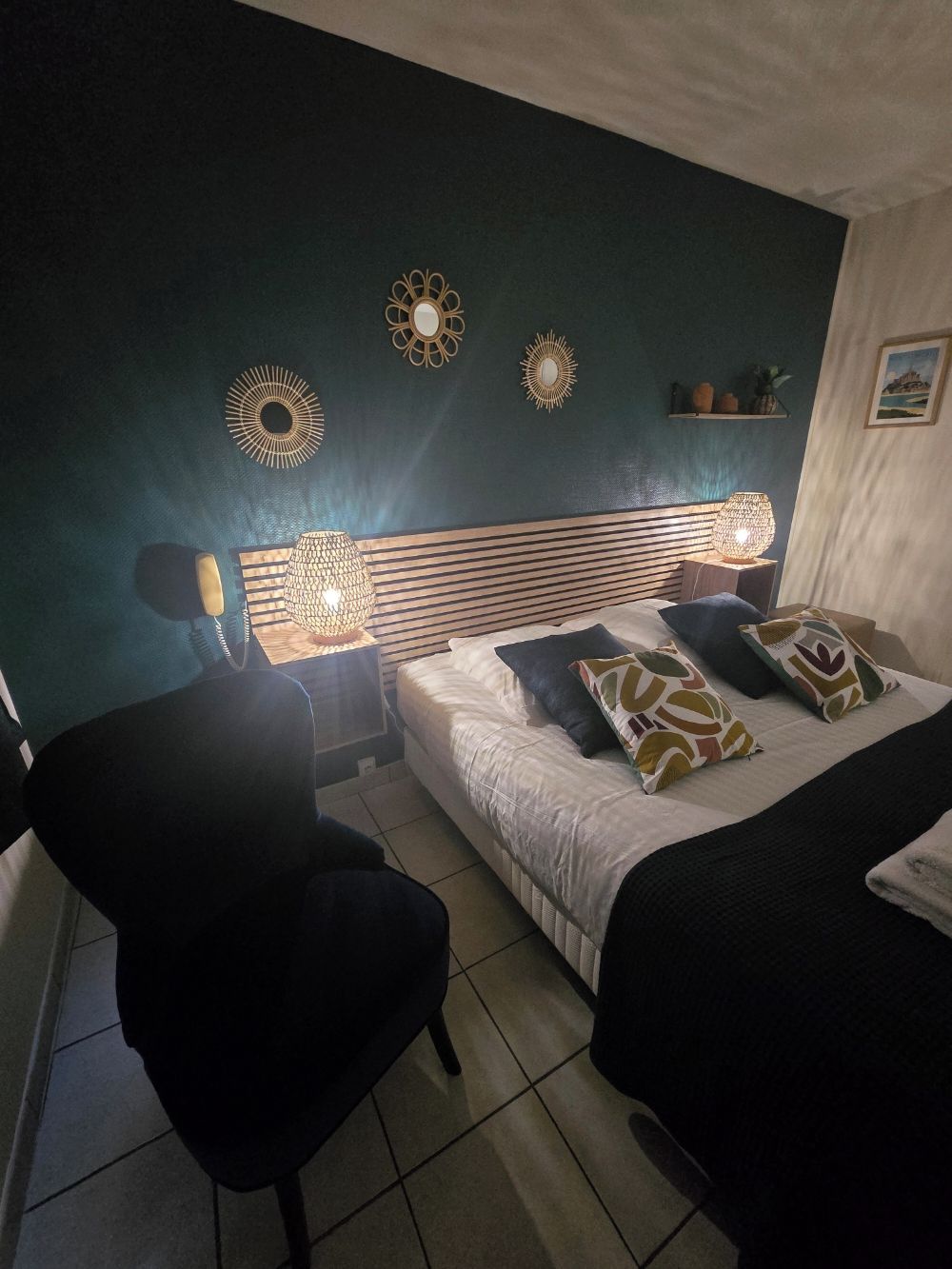 Una habitació amb un llit, una cadira i decoració mural.
