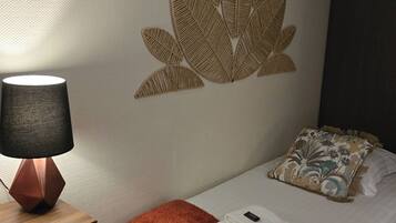 A neatly arranged hotel room with a bed, a bedside table with a lamp, and a wall decoration.