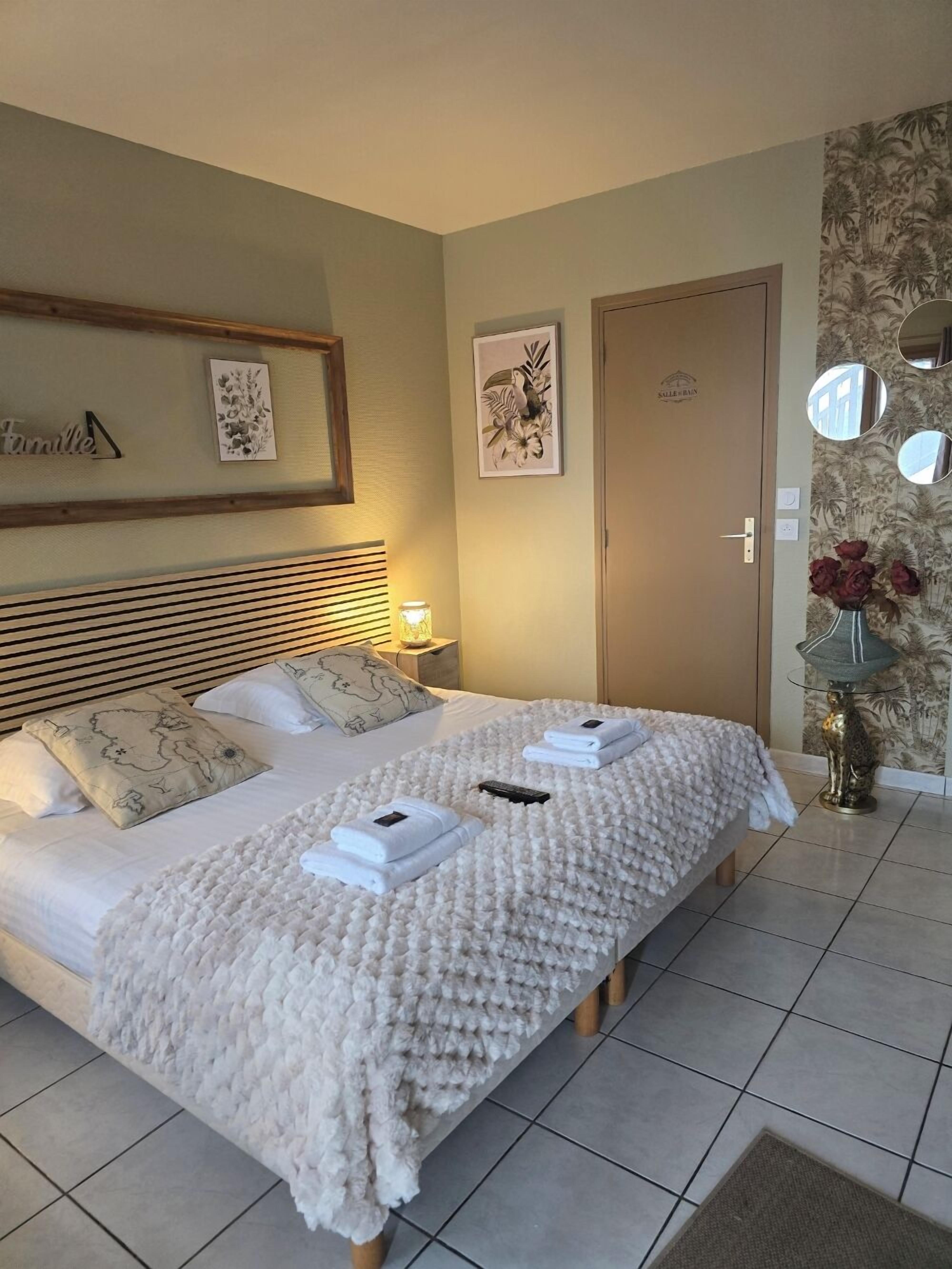 A double bed with a white quilt, two pillows, and a remote control on the bed.